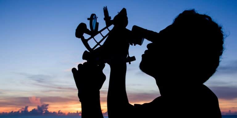 Silhouette of a sailor using a sextant