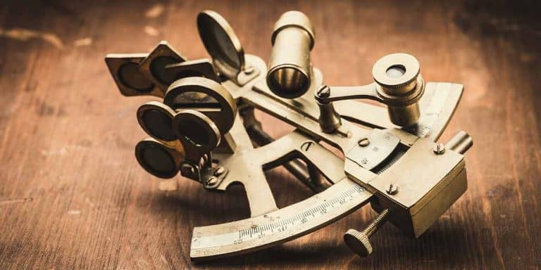 Brass sextant laying on a dark wooden floor