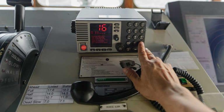 Hand reaching out to press the "CH16" button on a VHF radio