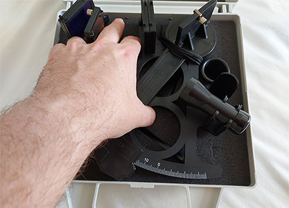 hand picking up a sextant from its case