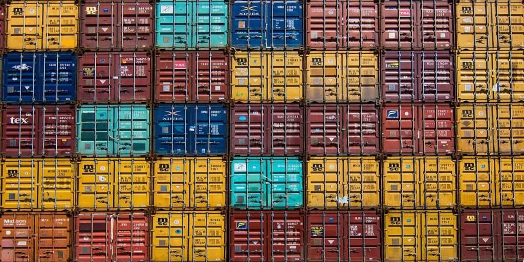 A photo showing many shipping containers of different colours stacked together